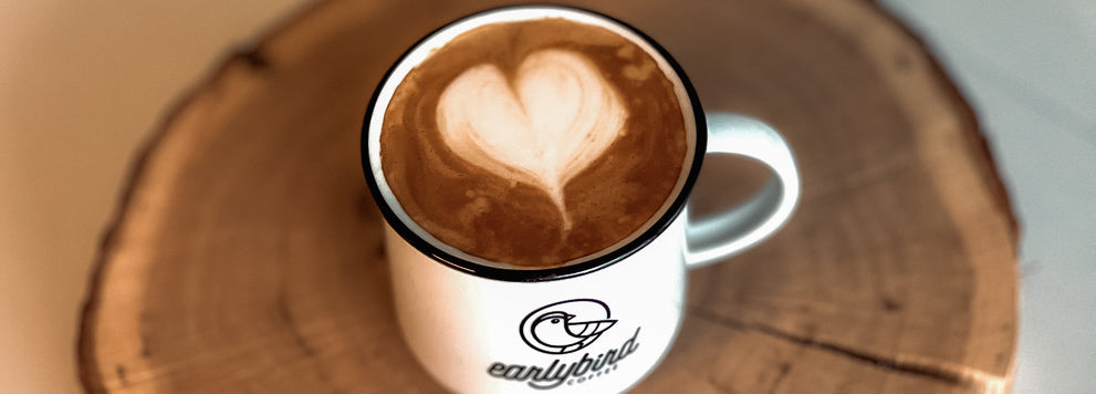 Cappuccino mit Herz im Milchschaum in der Keramiktasse von earlybird coffee auf einer Holzscheibe