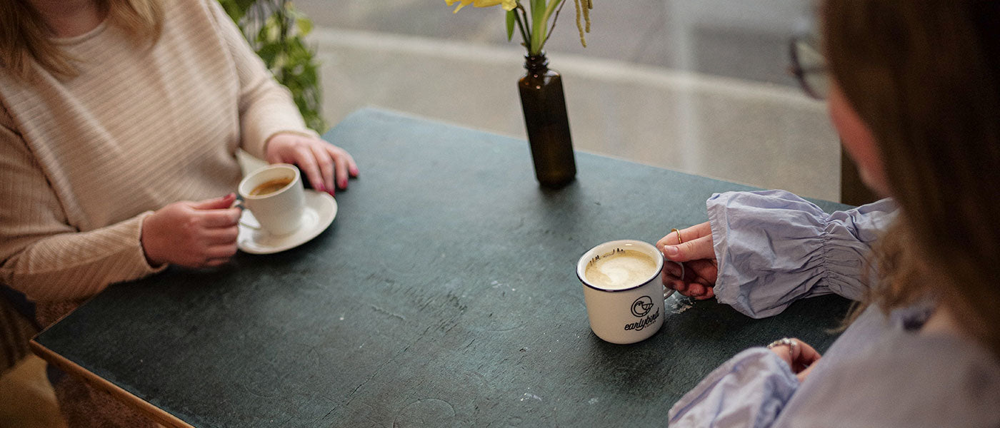 Bio Espresso und Cappuccino von earlybird coffee werden von zwei Frauen in gemütlicher Atmosphäre getrunken