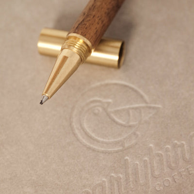 earlybird Kugelschreiber auf Holz liegt geöffnet auf einem Notizbuch